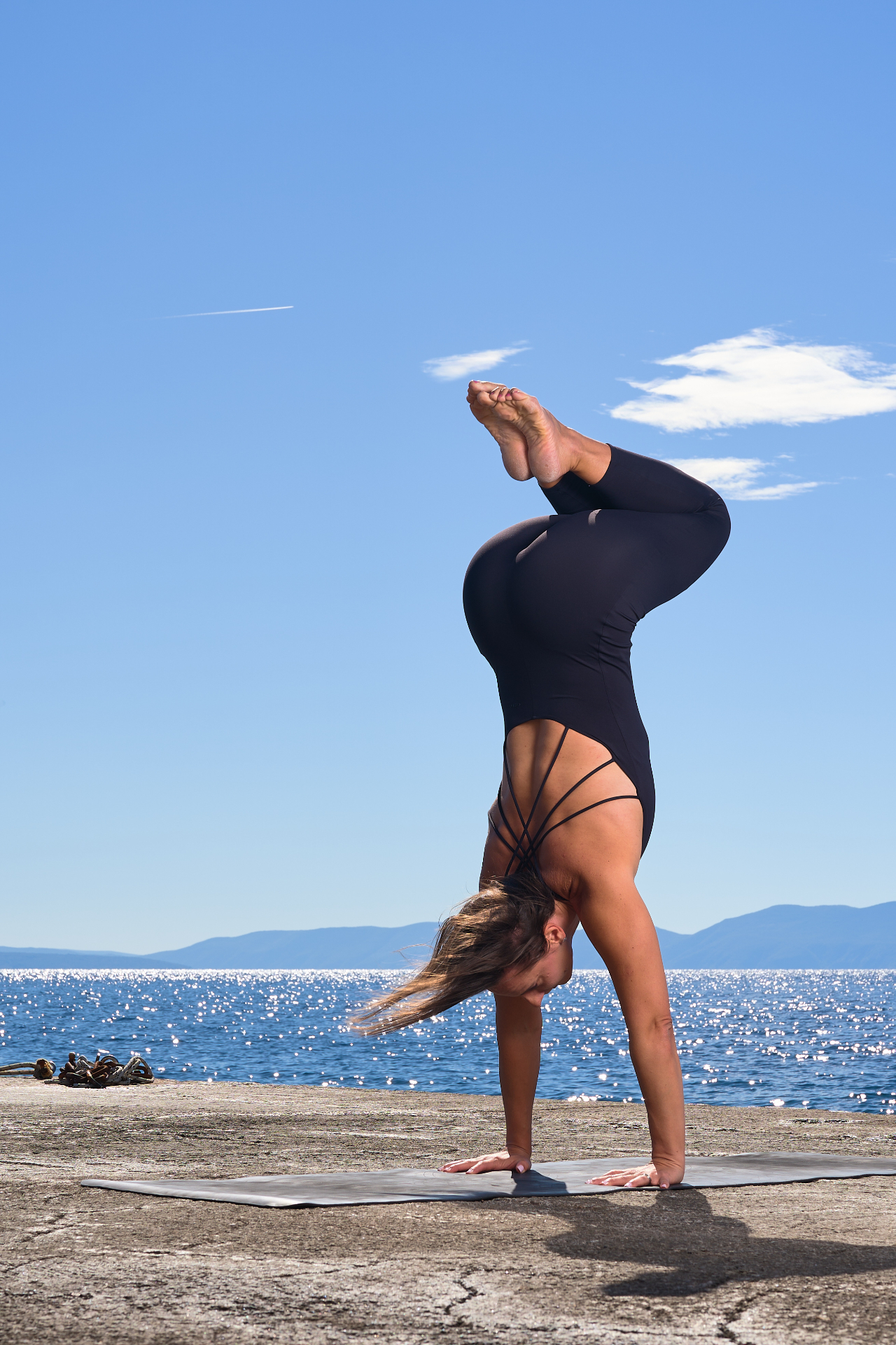 Trenerica u handstand pozi na molu uz more — Strong for Two coaching
